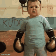 baby/small child in boxing gloves running hand across throat in menacing gesture