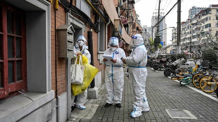 Health workers wearing protective gear visit homes in Jing’an district in Shanghai