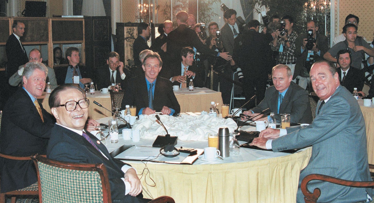 Five heads of state and government seated around a round table with photographers crowded behind them, turning to face the camera. Five heads of state and government seated around a round table with photographers crowded behind them, turning to face the camera.