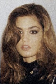 This may contain: an old photo of a woman with long hair and wearing a black leather jacket, looking at the camera