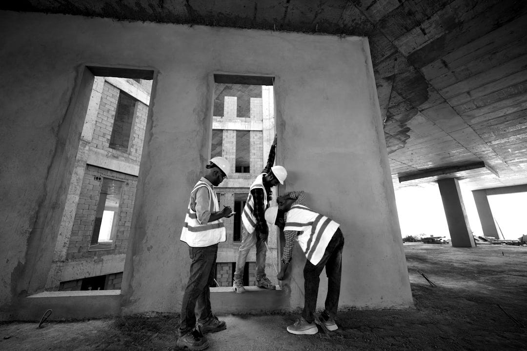 a group of men standing next to each other in front of a building a group of men standing next to each other in front of a building
