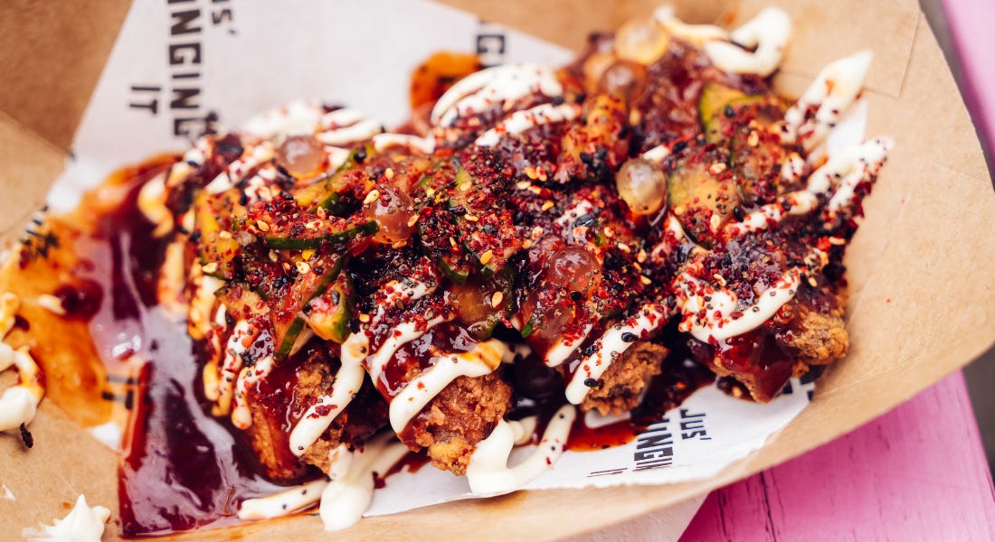 A box with barbecue chicken wings on it, on top of a pink picnic table