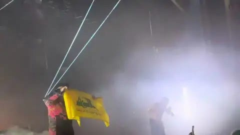 Kneecap-natsibändin jäsen heilutti lavalla Hizbollahin, islamonatsi-terroristijärjestön, lippua. Kyseinen terroristijärjestö on syyllistynyt kansanmurhiin ja lukuisiin hirmutekoihin. Kneecap-natsibändin jäsen heilutti lavalla Hizbollahin, islamonatsi-terroristijärjestön, lippua. Kyseinen terroristijärjestö on syyllistynyt kansanmurhiin ja lukuisiin hirmutekoihin.