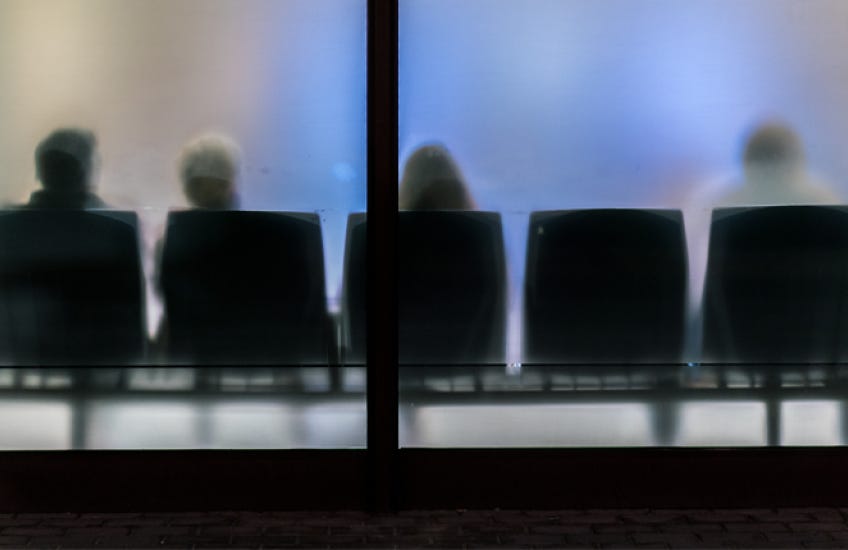 An abstract photograph of a waiting room with frosted glass and people sitting in chairs An abstract photograph of a waiting room with frosted glass and people sitting in chairs