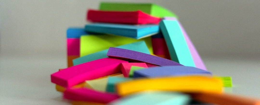 a pile of colored post it notes sitting on top of a table