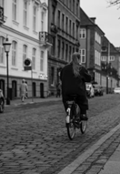 A monochrome photograph of a girl riding a bicycle down a cobbled street. A monochrome photograph of a girl riding a bicycle down a cobbled street.