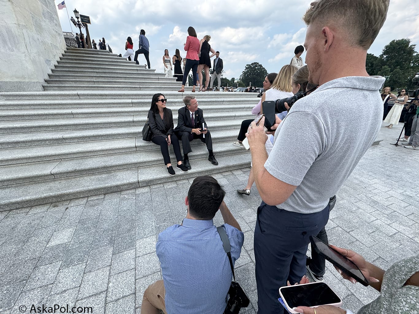 Man takes picture of two people sitting and talking on steps to a building © www.askapol.com Man takes picture of two people sitting and talking on steps to a building © www.askapol.com