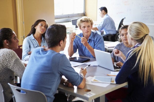 Teenagers working in a group around a table.