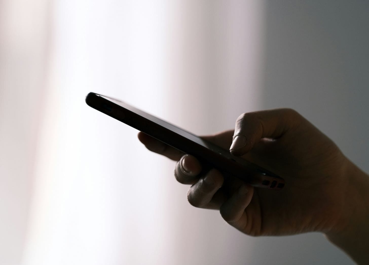 Person holding a smartphone in soft light, quietly reading a message Person holding a smartphone in soft light, quietly reading a message
