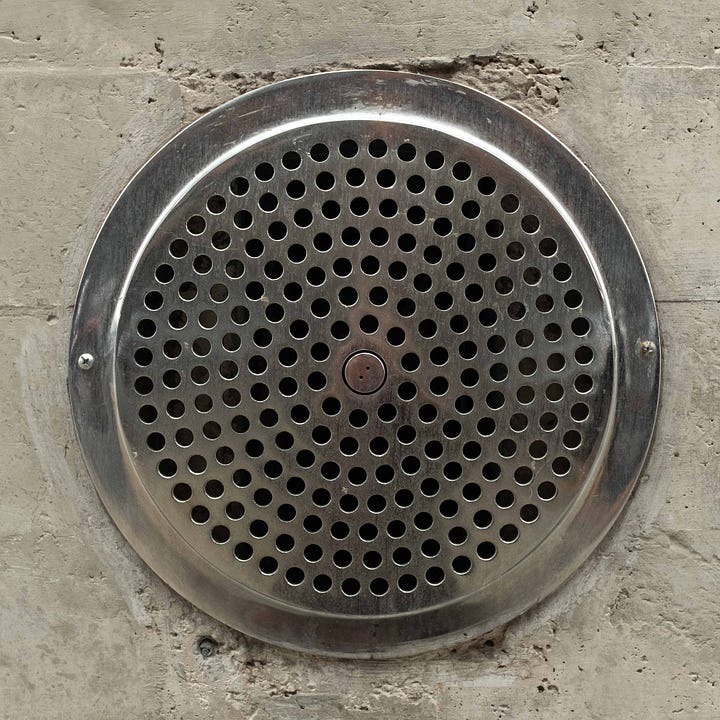 Diptych. Two circles. One like a radiating sun in concrete; the other a metal disk with holes.