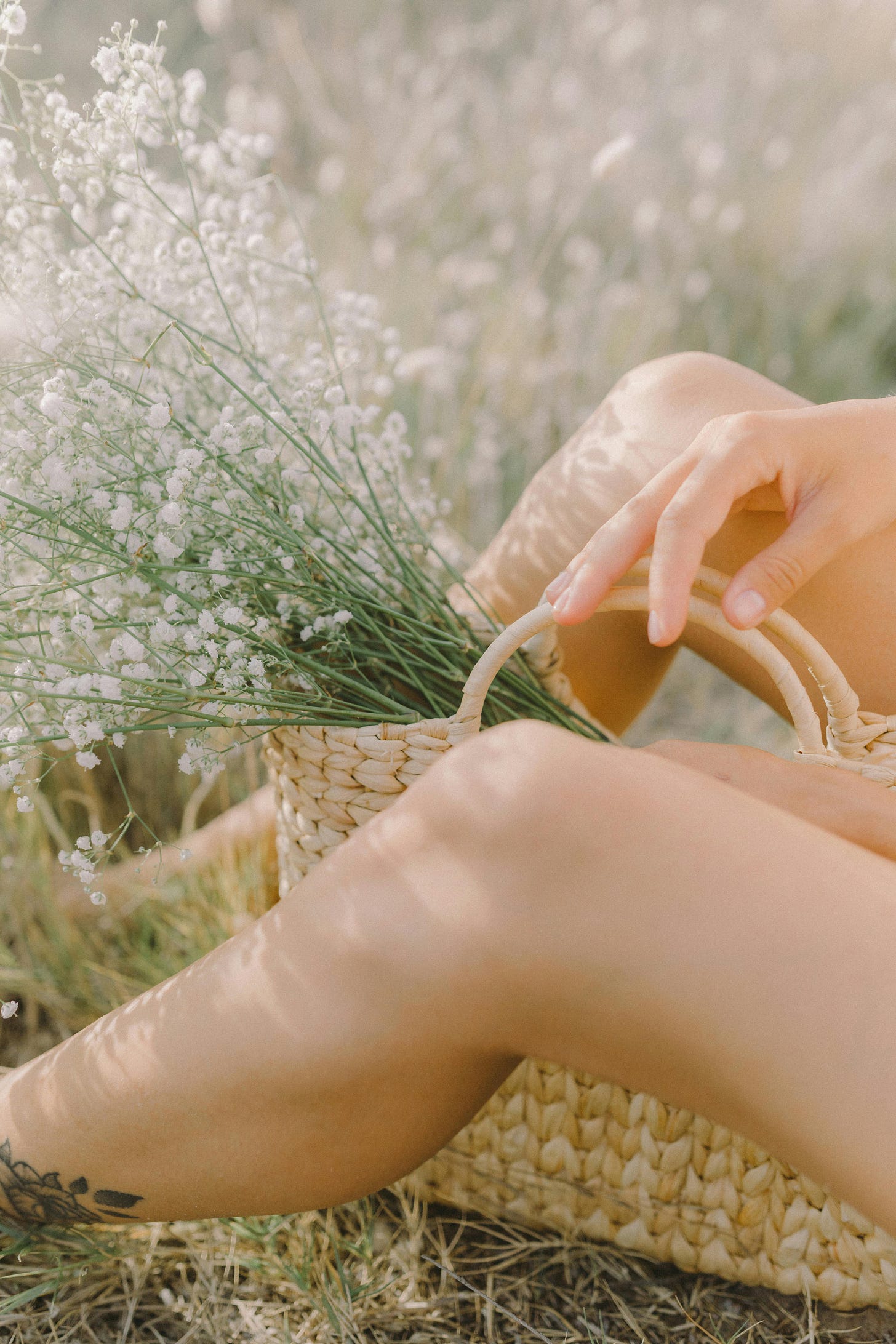 Free A serene scene of a person resting outdoors with a straw basket filled with flowers. Stock Photo