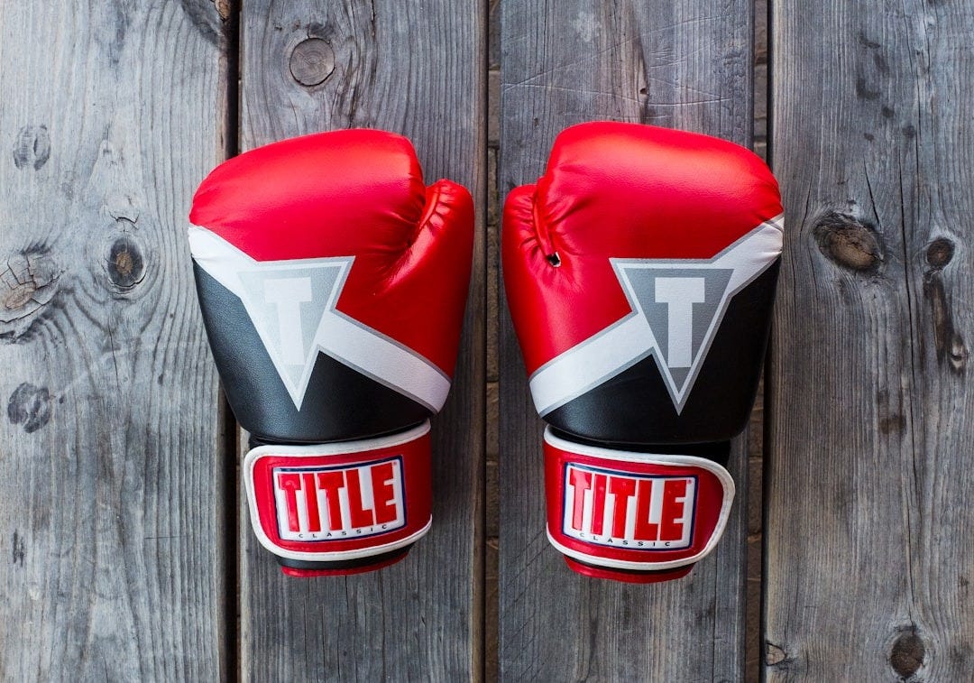 pair of red-and-black Title training gloves on grey wooden plank