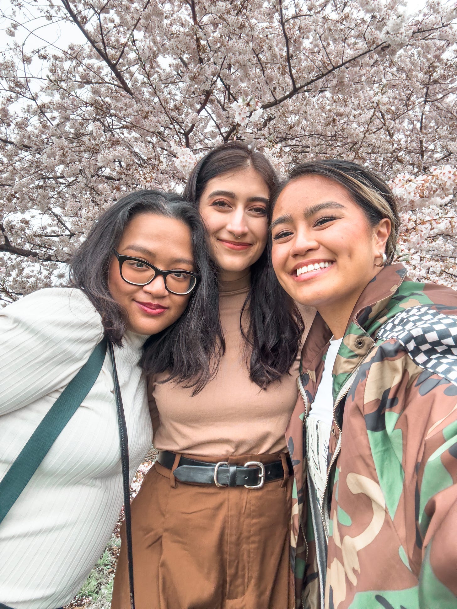 Ysabelle, Maddie, and Joelle taking a group selfie in front of a cherry blossom tree