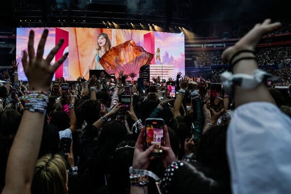 Images of Taylor Swift are projected on a giant screen during a performance. 