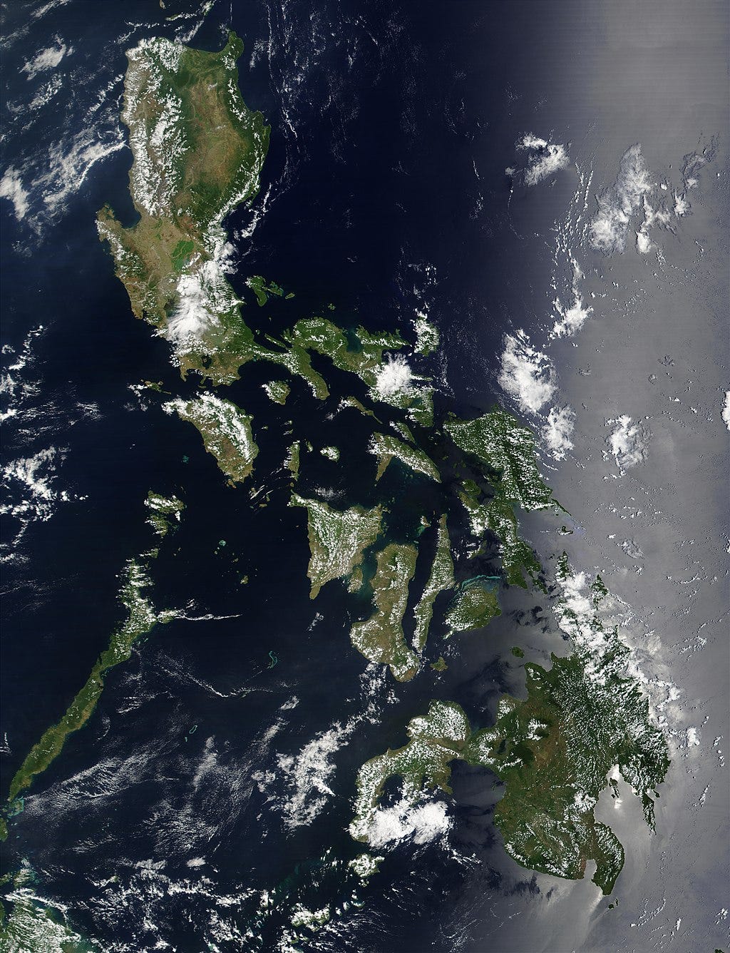 satellite image of the Philippines, there are clouds covering some of the islands which appear brown and green. the ocean is dark blue