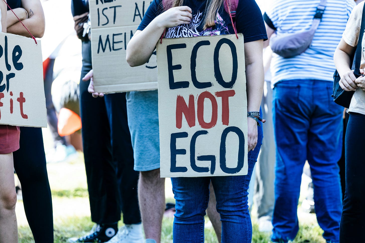 Taken at a protest with lots of people standing around. The person in the front of the photo holds a sign that reads ECO NOT EGO. Taken at a protest with lots of people standing around. The person in the front of the photo holds a sign that reads ECO NOT EGO.