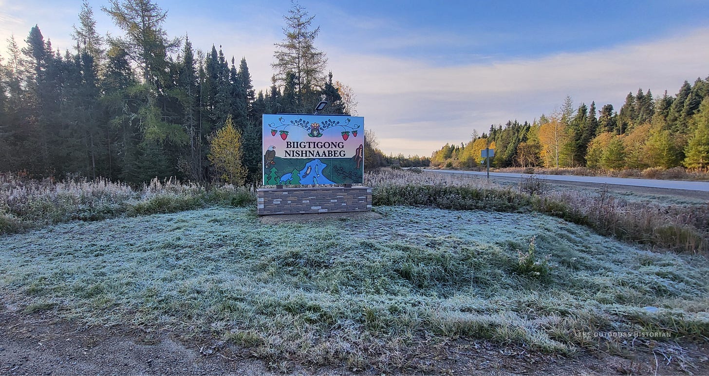 A sign for Biigtigong Nishnaabeg Nation set against a backdrop of frosted green grass.