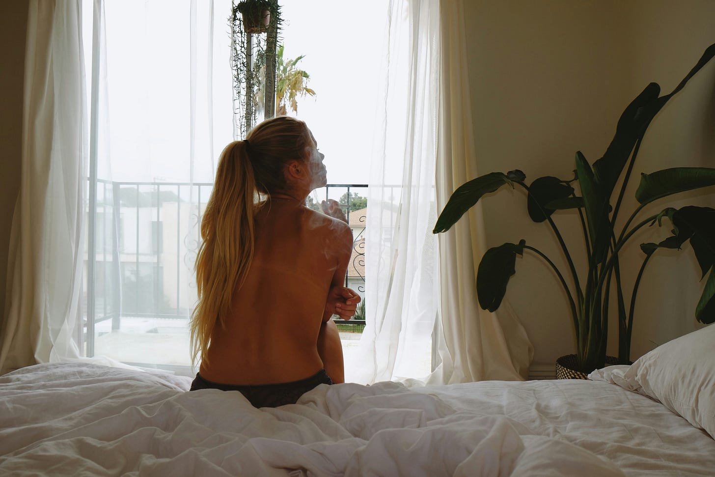  Woman topless facing away and sitting on bed 