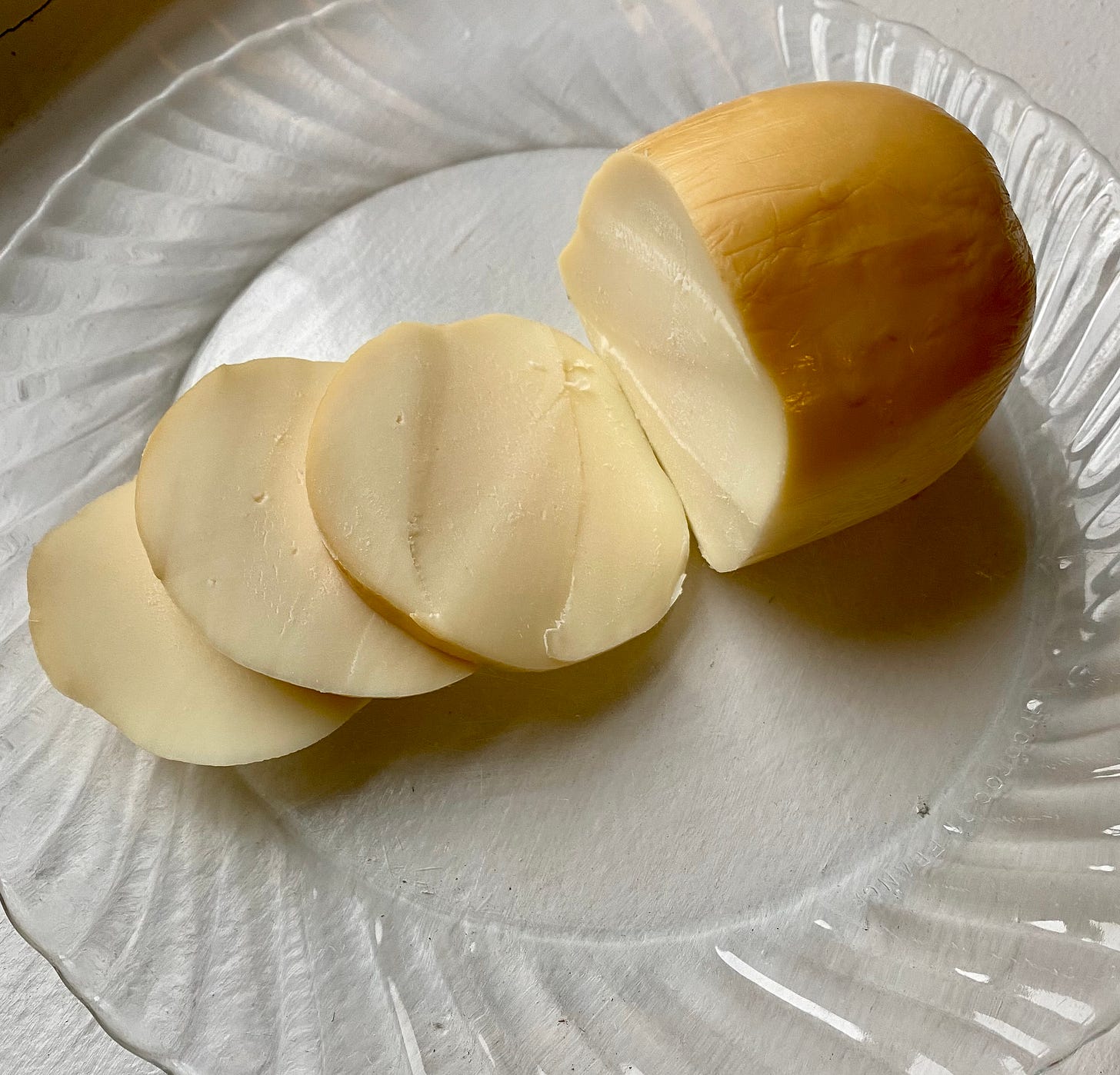 ball of smoked mozzarella, sliced, on a clear plate