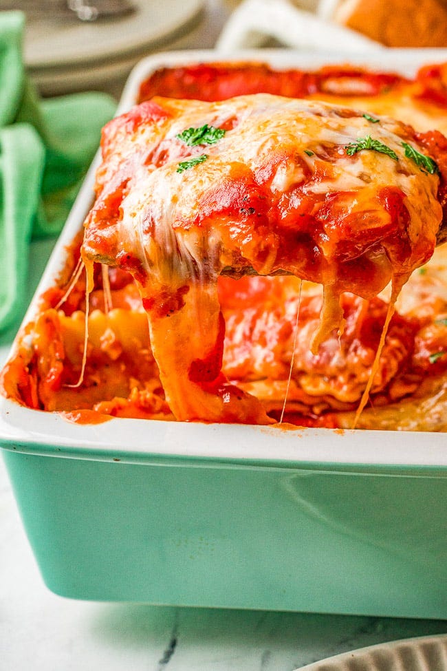 A serving of cheese ravioli lasagna being lifted from a baking dish. 