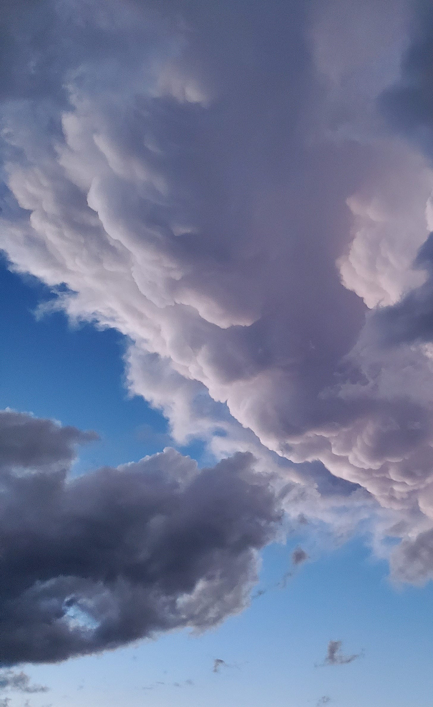 Photo of clouds tumbling through the sky, bright white contrasting with darker ominous sections with bright blue sky poking through Photo of clouds tumbling through the sky, bright white contrasting with darker ominous sections with bright blue sky poking through