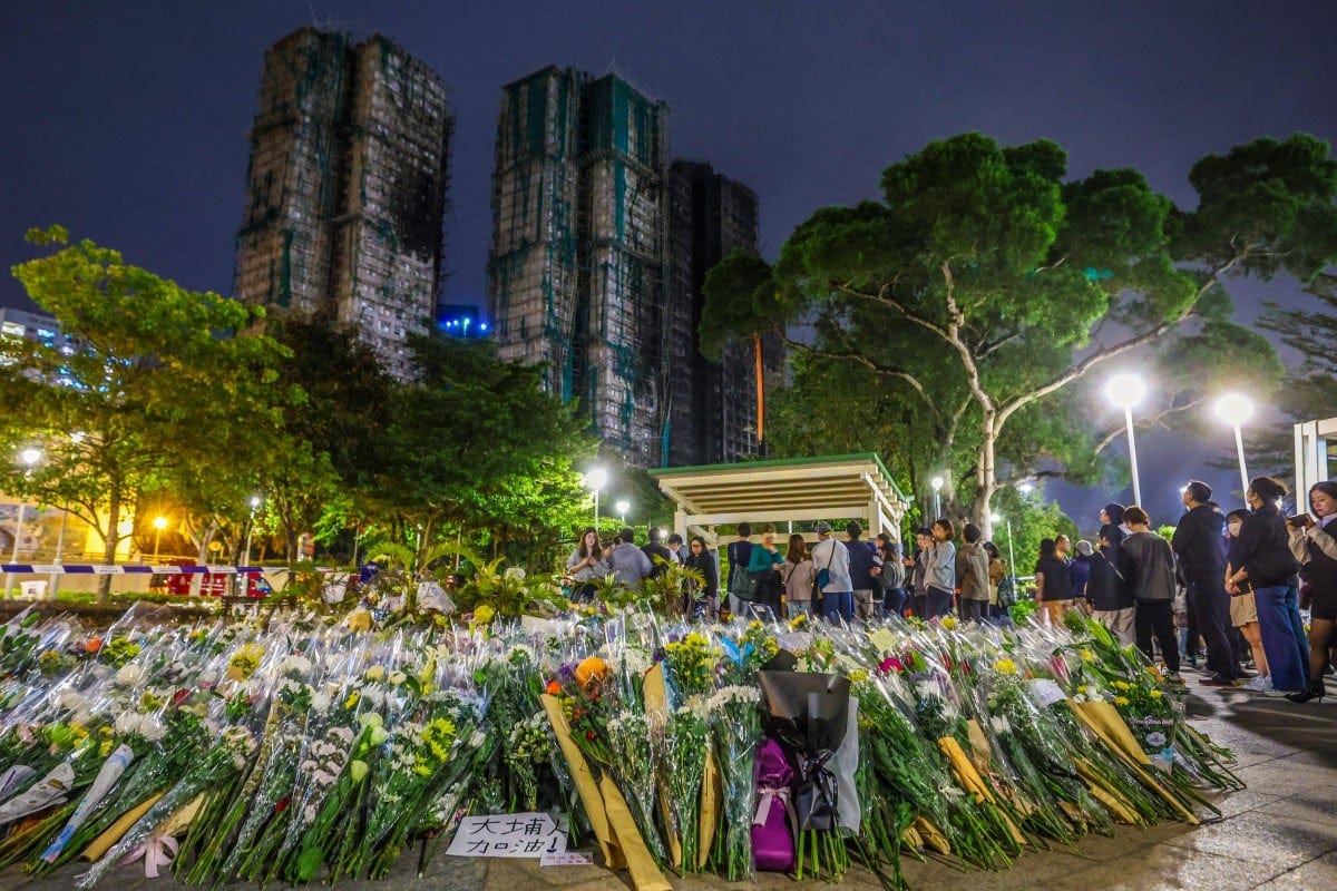 Floral tributes continue to grow near the scene of the tragedy in Tai Po, with Wang Fuk Court in the background. Photo: Edmond So