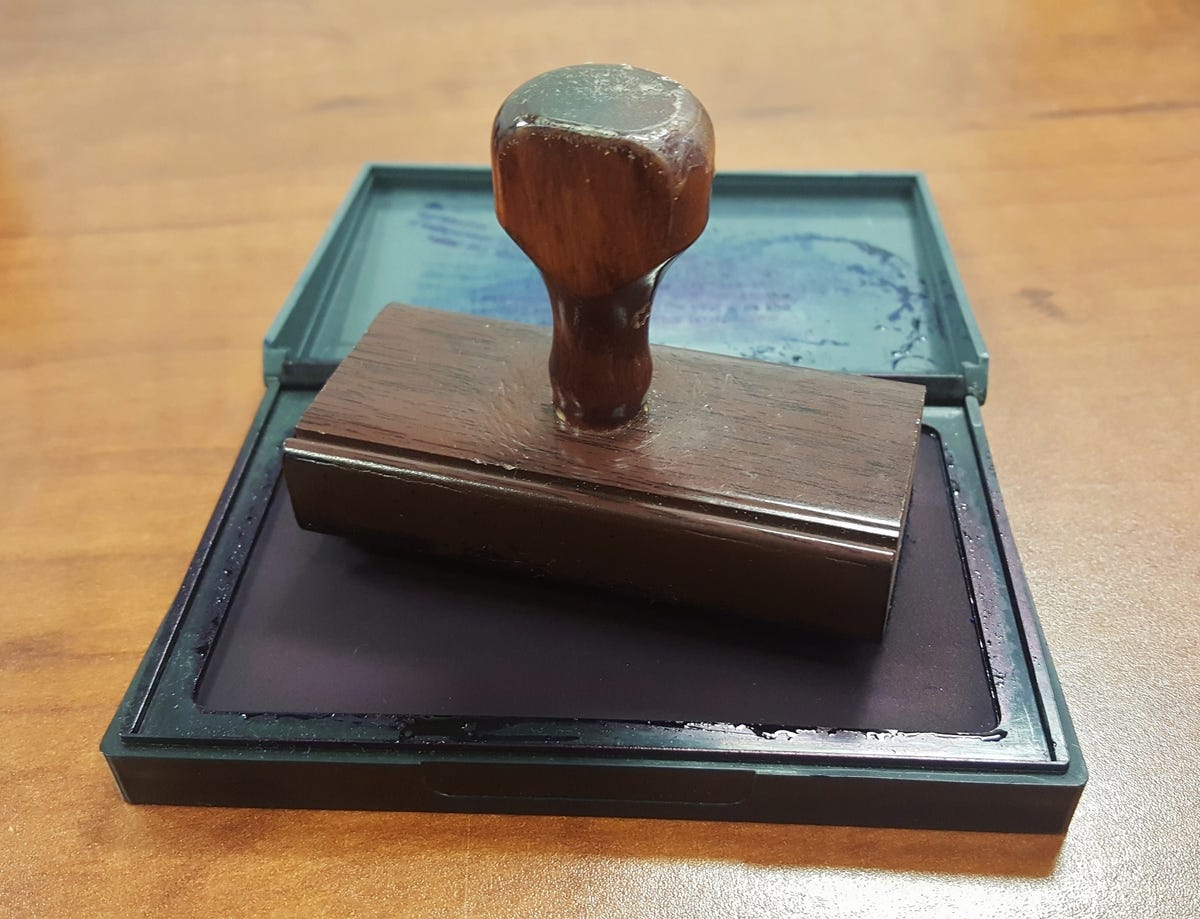 A worn rubber stamp sitting in an open ink pad.