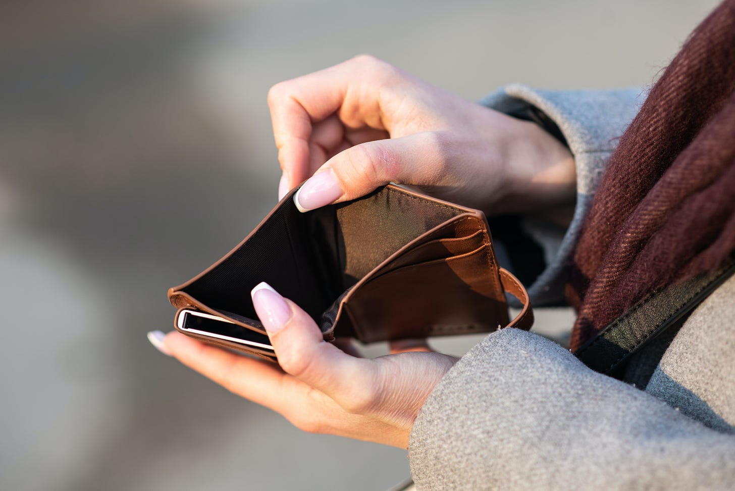 A person holding a wallet open, showing it is empty A person holding a wallet open, showing it is empty