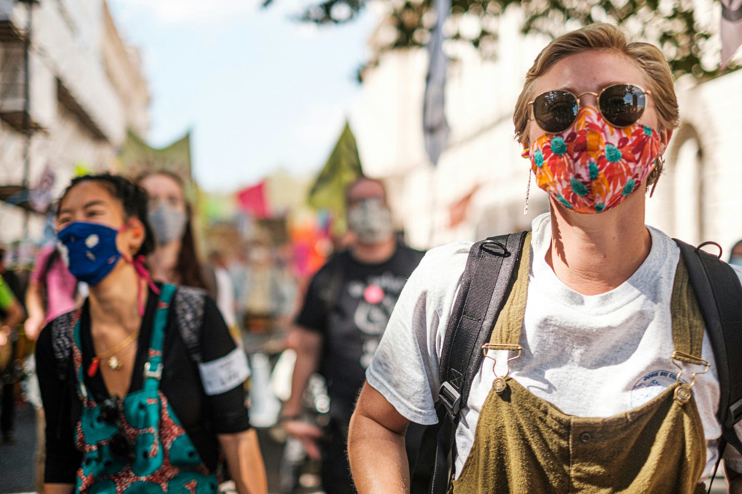 Color photo of a group of masked protestors walking down a city street