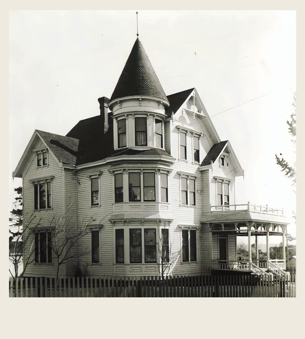Historic photograph of a large Victorian house with a turret and wraparound porch, seen from the street.