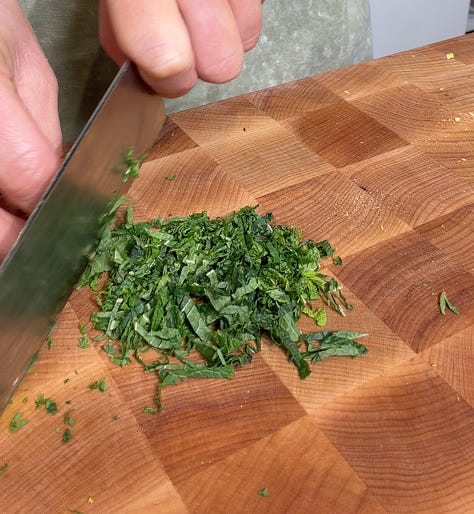 Whipped ricotta in a food processor with a spatula, Finely chopped pistachios and thinly sliced fresh mint being chopped on a wooden cutting board for skewer topping