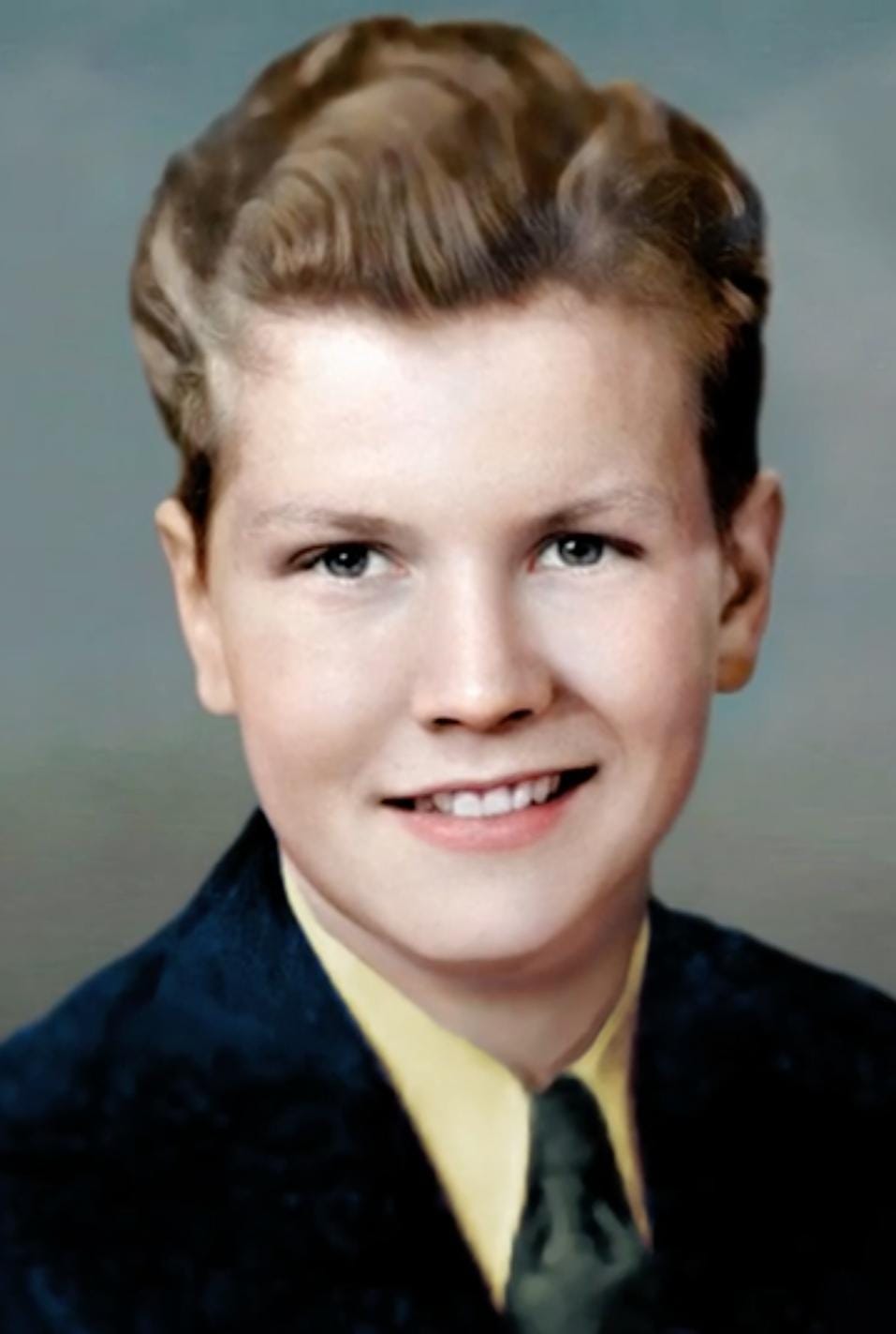 A colorized photograph of a young man in a suit.