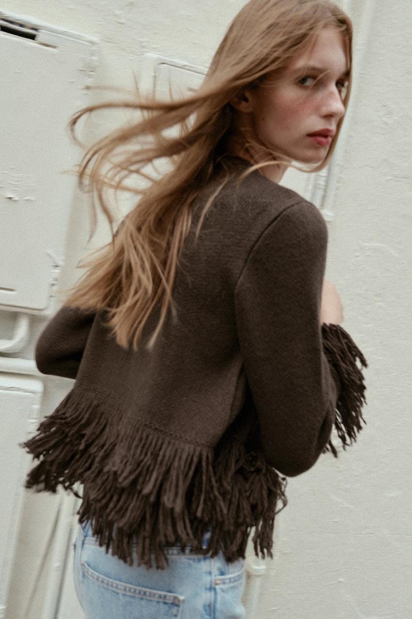 Medium shot of a brown jacket with fringe on the bottom and long sleeves.