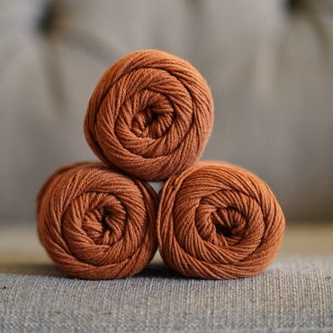 A stack of three skeins of orange yarn