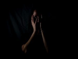 woman in the dark, holding her face woman in the dark, holding her face