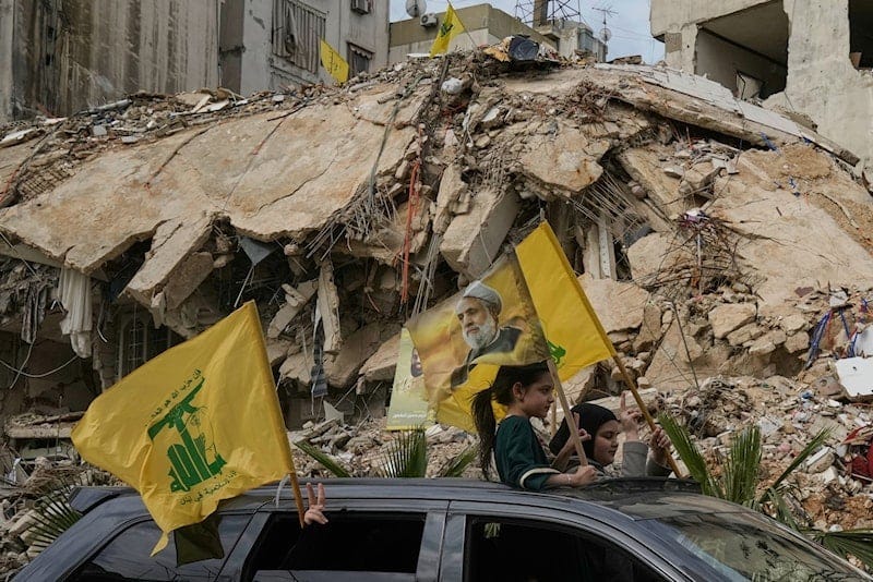 Displaced residents wave Hezbollah flags, including one bearing a picture of its leader, Sheikh Naim Qassem, as they pass rubble of destroyed buildings in Dahiyeh, Beirut's southern suburbs, Lebanon, April 17, 2026 (AP) Displaced residents wave Hezbollah flags, including one bearing a picture of its leader, Sheikh Naim Qassem, as they pass rubble of destroyed buildings in Dahiyeh, Beirut's southern suburbs, Lebanon, April 17, 2026 (AP)
