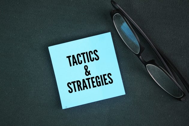 Glasses and colored paper with the words tactics and strategies.