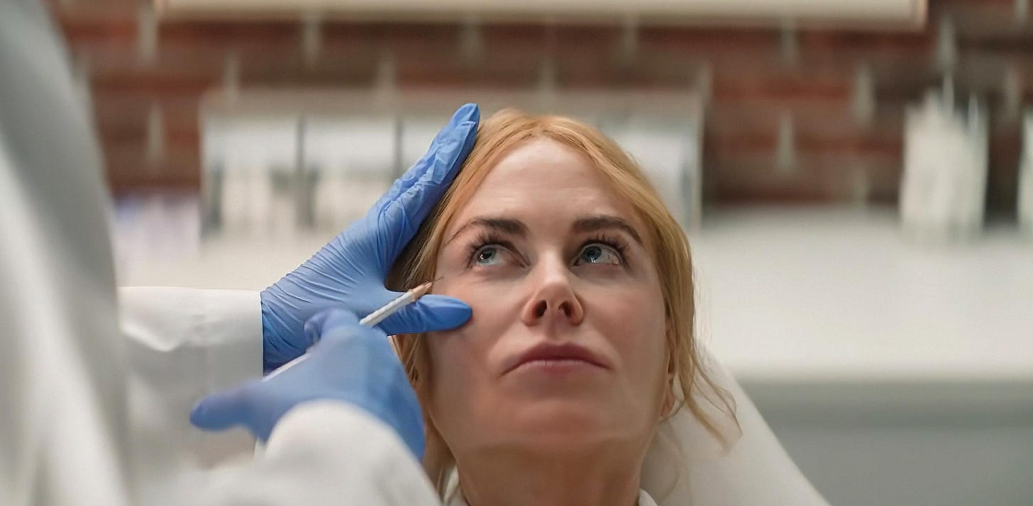 Nicole Kidman in Babygirl. A headshot of the actor getting an injection of Botox beside her eyes. A gloved hand of a medical professional gives her the jab as Kidman looks on seriously. 