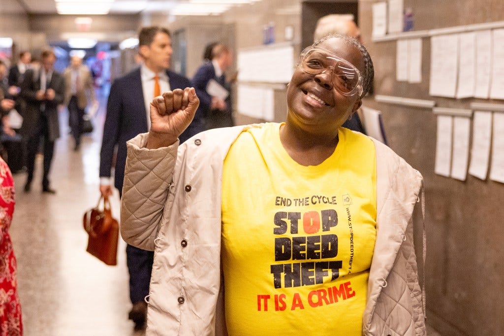 Carmella Charrington in a "Stop Deed Theft" T-shirt raises her fist at a courthouse.