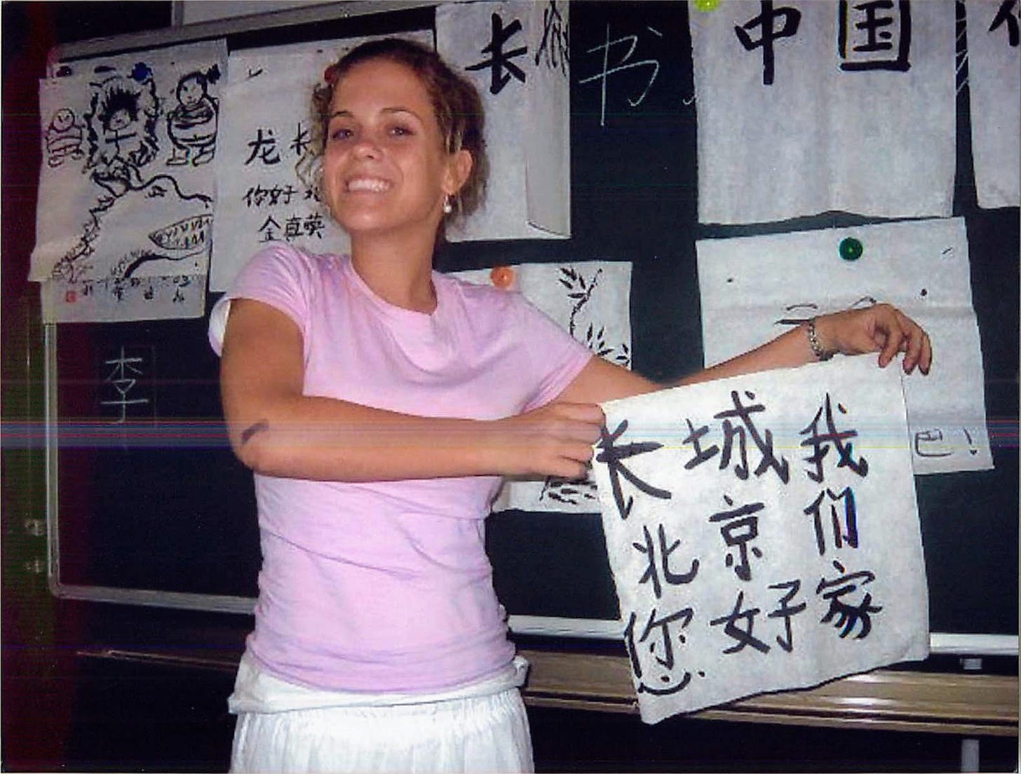 A young Caroline Davis holding a handwritten Chinese calligraphy scroll during a summer program in China A young Caroline Davis holding a handwritten Chinese calligraphy scroll during a summer program in China