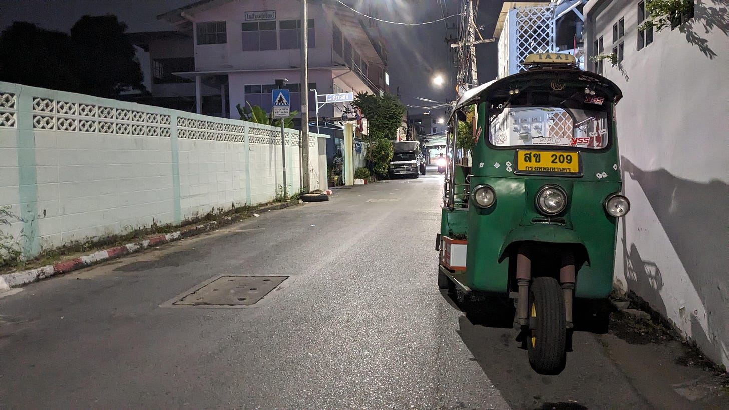 a tuk tuk sits on a dark street