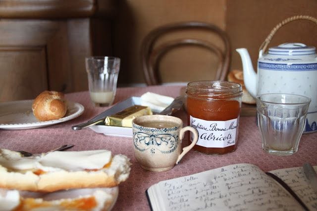 This may contain: an open book on a table next to some food and cups with saucers in front of it This may contain: an open book on a table next to some food and cups with saucers in front of it