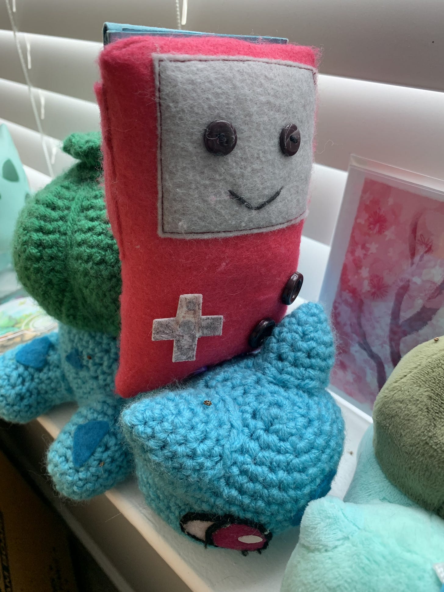 A photograph of Ferretsroq’s crochet Bulbasaur with a felt Game Boy Color, gifts from his friends that mean an awful lot to him A photograph of Ferretsroq’s crochet Bulbasaur with a felt Game Boy Color, gifts from his friends that mean an awful lot to him