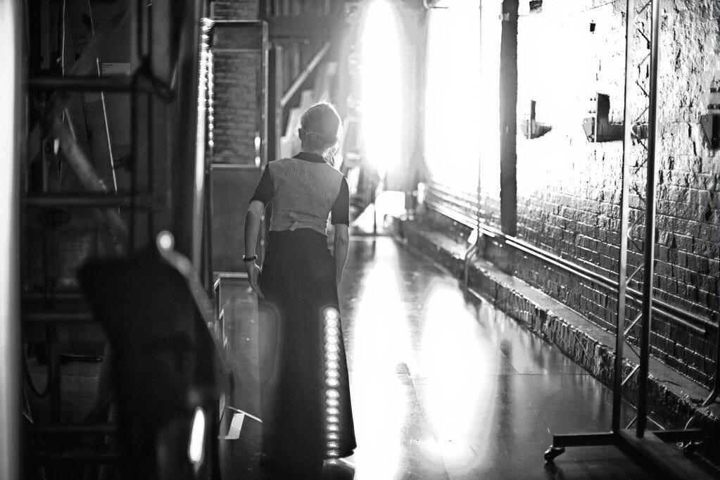 An improviser in the wings. Her back is to us and she looks out into the big west end stage An improviser in the wings. Her back is to us and she looks out into the big west end stage