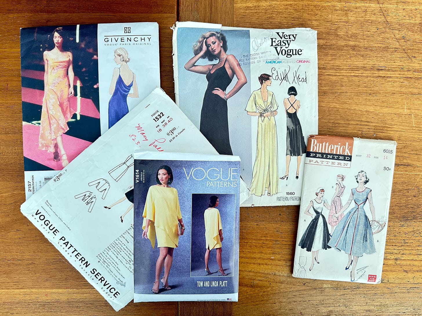 New and vintage designer sewing patterns displayed together, showing a range of prices. Clockwise from the bottom center: Tom and Linda Platt for Vogue priced at $25, a vintage Balmain for Vogue pattern priced at $3, a Givenchy for Vogue pattern priced at $25, an Edith Head for Vogue pattern priced at $4.50, and a Butterick sewing pattern priced at $0.50.
