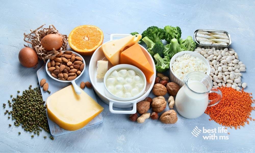 A table laden with calcium rich foods including figs, almonds, oranges, broccoli, lentils, eggs, sardines. And, yes, cheese.