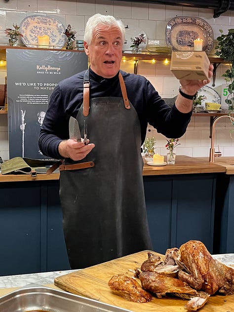 Paul Kelly of the Kelly Bronze company, standing behind a counter demonstrating carving technique.
