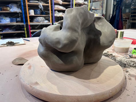 With views from different angles, 10" greenware sculpture form sitting on a wooden turn table on a clay studio table