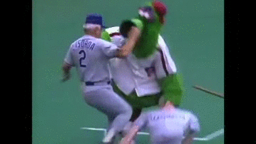 Tommy Lasorda assaults the Phillie Phanatic with his own effigy. Tommy Lasorda assaults the Phillie Phanatic with his own effigy.