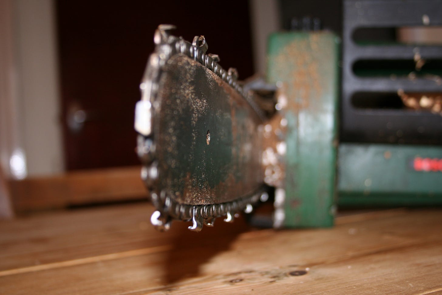 A chainsaw sits on a table, the tip of its blade pointing toward the viewer. 